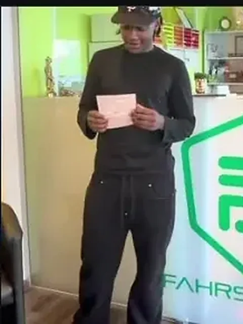 Fahrschüler mit bestandener Prüfung vor dem DEVAM-Banner in der Fahrschule