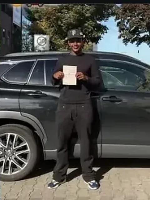 Fahrschüler mit Prüfungsbescheinigung neben einem Auto