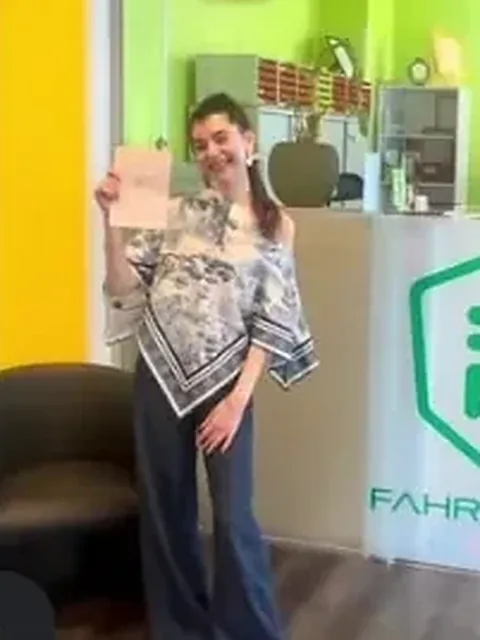Fahrschülerin mit Prüfungsbescheinigung in den Räumen der Fahrschule